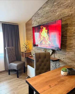 a living room with a large television on a brick wall at Apartmani Mir Kopaonik in Kopaonik