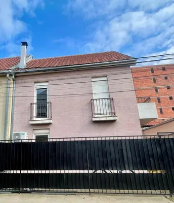 a pink house with windows and a black fence at Kuća Vujović in Niš