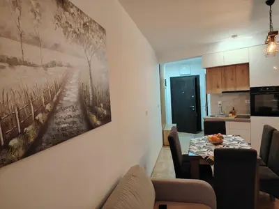 a living room with a table and a painting on the wall at Apartman Bonbon in Vrnjačka Banja