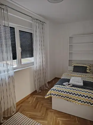 a bedroom with a bed and two windows at Apartman Bonbon in Vrnjačka Banja