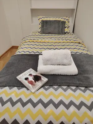 a bed with two towels and a book on it at Apartman Bonbon in Vrnjačka Banja