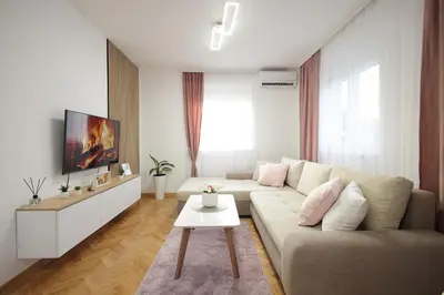 a white living room with a couch and a tv at Apartman Babić Lux in Vrnjačka Banja