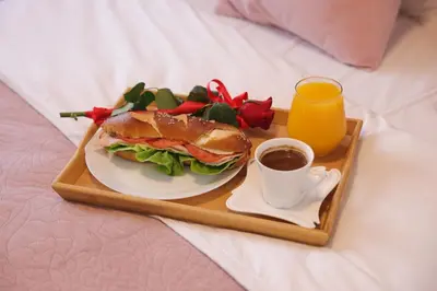 a tray with a sandwich and a cup of coffee on a bed at Apartman Babić Lux in Vrnjačka Banja