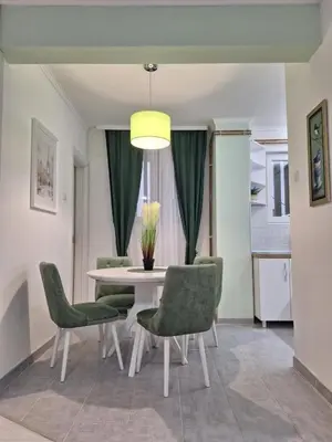 a dining room with a table and green chairs at Apartman Nikola Vukosavljevic in Kruševac