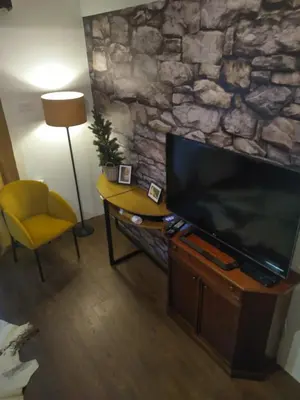 a living room with a large television and a yellow chair at Rezervat in Jelašnica