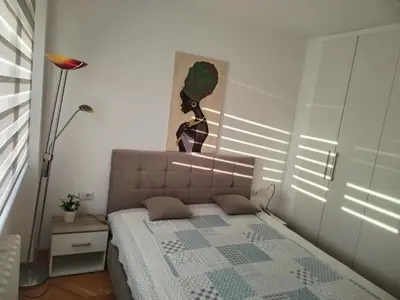 a bedroom with a bed with a painting on the wall at Lunjica in Niš