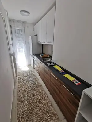 a kitchen with white cabinets and a black counter top at Lunjica in Niš