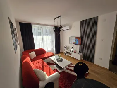 a living room with a red couch and a table at Apartman Nikolić in Soko Banja