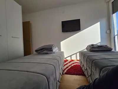 a bedroom with two beds and a tv on the wall at Apartman Nikolić in Soko Banja