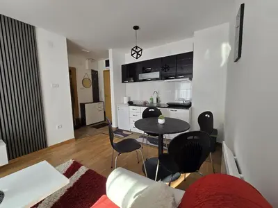 a living room with a table and chairs and a kitchen at Apartman Nikolić in Soko Banja