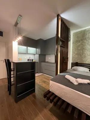 a bedroom with a large bed and a kitchen at LiboroPlanet in Niš