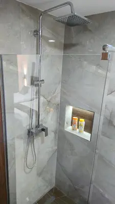a shower with a glass door in a bathroom at California Apartments in Niš