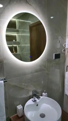a bathroom with a sink and a round mirror at California Apartments in Niš
