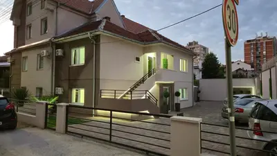 a white house with green doors on a street at California Apartments in Niš
