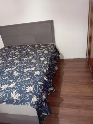 a bed with a black and white comforter and a wooden floor at Seoska idila in Bela Palanka