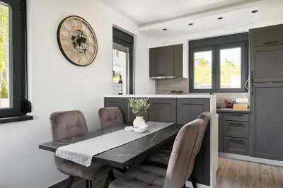 a kitchen with a table with chairs and a clock on the wall at Vision apartmani Goč in Goč