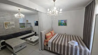 a bedroom with a bed and a couch and a chandelier at Kristal in Niš