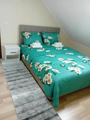 a bed with a blue comforter with flowers on it at Apartman Anči in Vrnjačka Banja
