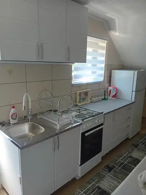 a kitchen with white cabinets and a sink and a refrigerator at Apartman Anči in Vrnjačka Banja