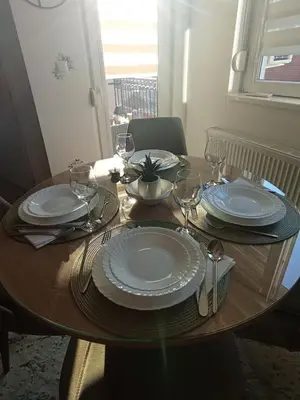 a wooden table with plates and wine glasses on it at Apartman Biser Vranja - FREE PARKING - CITY CENTER in Vranje