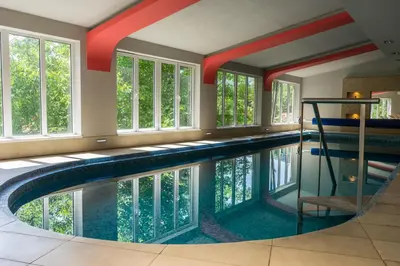 a swimming pool in a house with windows at Spa & wellness Villa Garetov Konak in Prolomska Banja