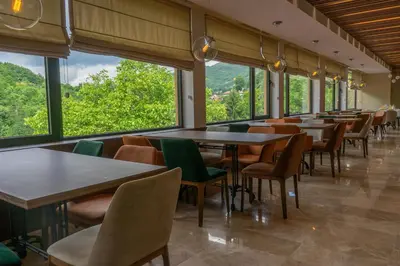 a dining room with tables and chairs and windows at Spa & wellness Villa Garetov Konak in Prolomska Banja