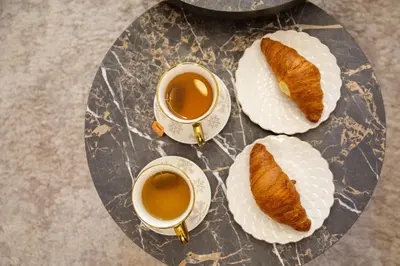 a glass table with two cups of tea and bread at Premium Planet Deluxe & SPA in Niš