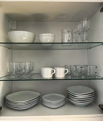 a shelf with plates and bowls and glasses on it at Mars apartman in Vrnjačka Banja