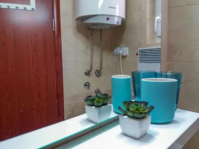 a bathroom counter with three blue cups and plants at Mars apartman in Vrnjačka Banja