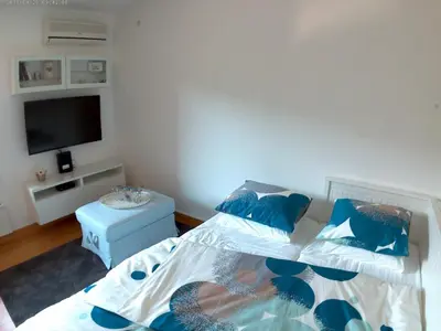 a bedroom with a bed with blue pillows and a tv at Mars apartman in Vrnjačka Banja