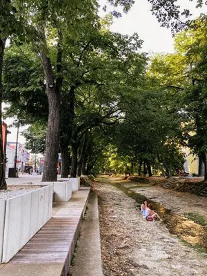 two children sitting on the ground in a park at Mars apartman in Vrnjačka Banja