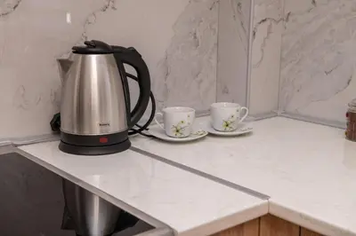 a tea kettle and two cups on a counter at Apartman Tasic in Vranje