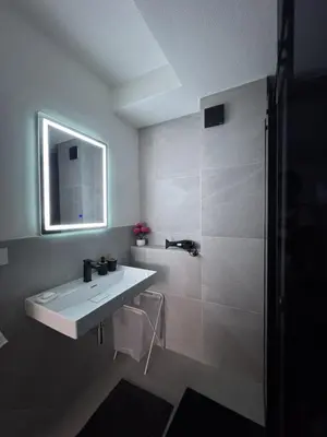 a white bathroom with a sink and a shower at Apartman Tasic in Vranje