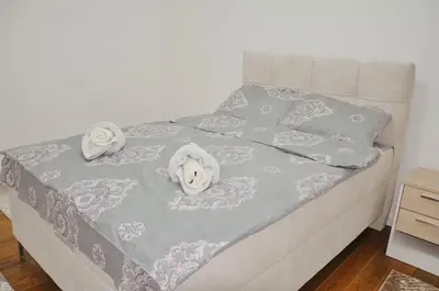 a bed with a blue bedspread with a stuffed animal on it at Planet Urban Apartment & SPA in Niš