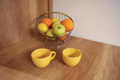 a basket of fruit with two cups on a table at Apartment Story Nis in Niš