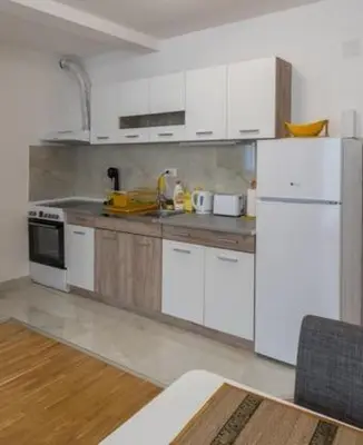a kitchen with white cabinets and a white refrigerator at Sunshine Lux in Vrnjačka Banja