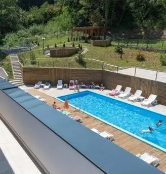 a large swimming pool with people laying on chairs in it at Sunshine Lux in Vrnjačka Banja