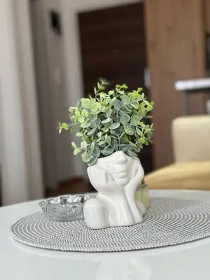 a white vase with green plants in it on a table at Royal apartmani Vrnjačka Banja in Vrnjci