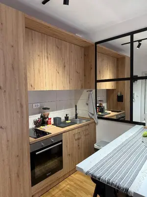 a kitchen with wooden cabinets and a stove top oven at Royal apartmani Vrnjačka Banja in Vrnjci