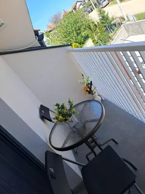 a small balcony with a glass table and chairs at Apartman S&U in Soko Banja