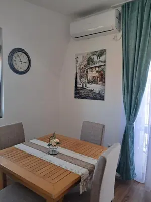 a dining room table with a clock on the wall at Apartman S&U in Soko Banja