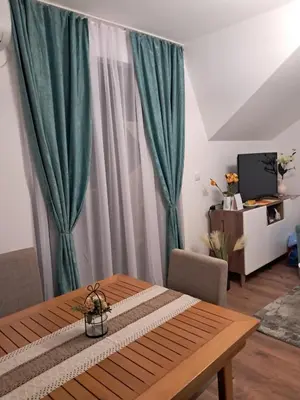 a dining room with a table and a green curtain at Apartman S&U in Soko Banja