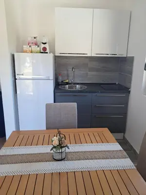 a kitchen with a wooden table and a refrigerator at Apartman S&U in Soko Banja