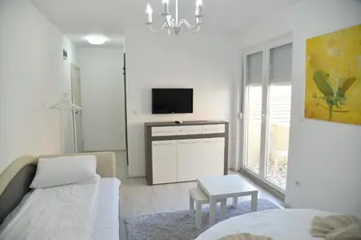 a white living room with a bed and a tv at Ribarski Konaci in Ribarska Banja