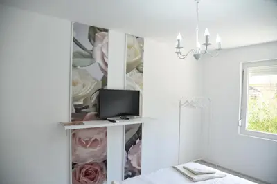 a room with a tv and a wall with flowers at Ribarski Konaci in Ribarska Banja