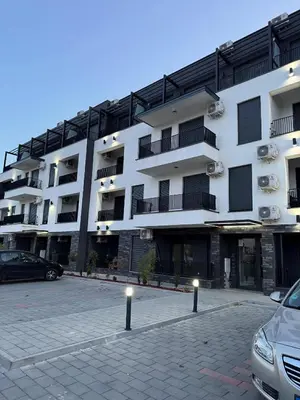 a large white building with cars parked in a parking lot at Apartman CRYSTAL Vrnjačka Banja in Vrnjačka Banja
