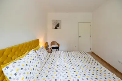 a bedroom with a bed with a yellow headboard at Apartman ZVONKO in Vrnjačka Banja