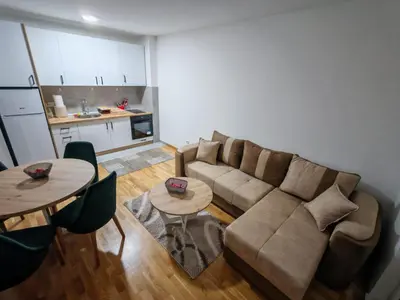 a living room with a couch and tables and a kitchen at Apartman STEFAN in Vrnjačka Banja