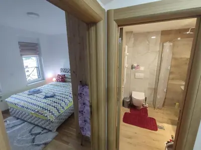 a small bedroom with a bed and a glass door at Apartman STEFAN in Vrnjačka Banja