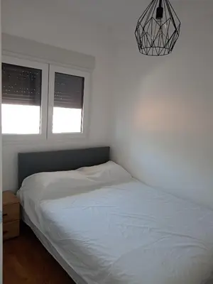 a bedroom with a white bed and two windows at Moj kutak Sokobanja in Soko Banja